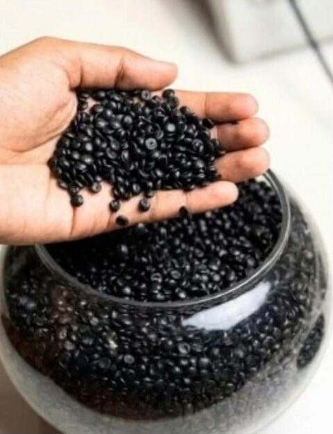 Black LD granules held over a jar of granules